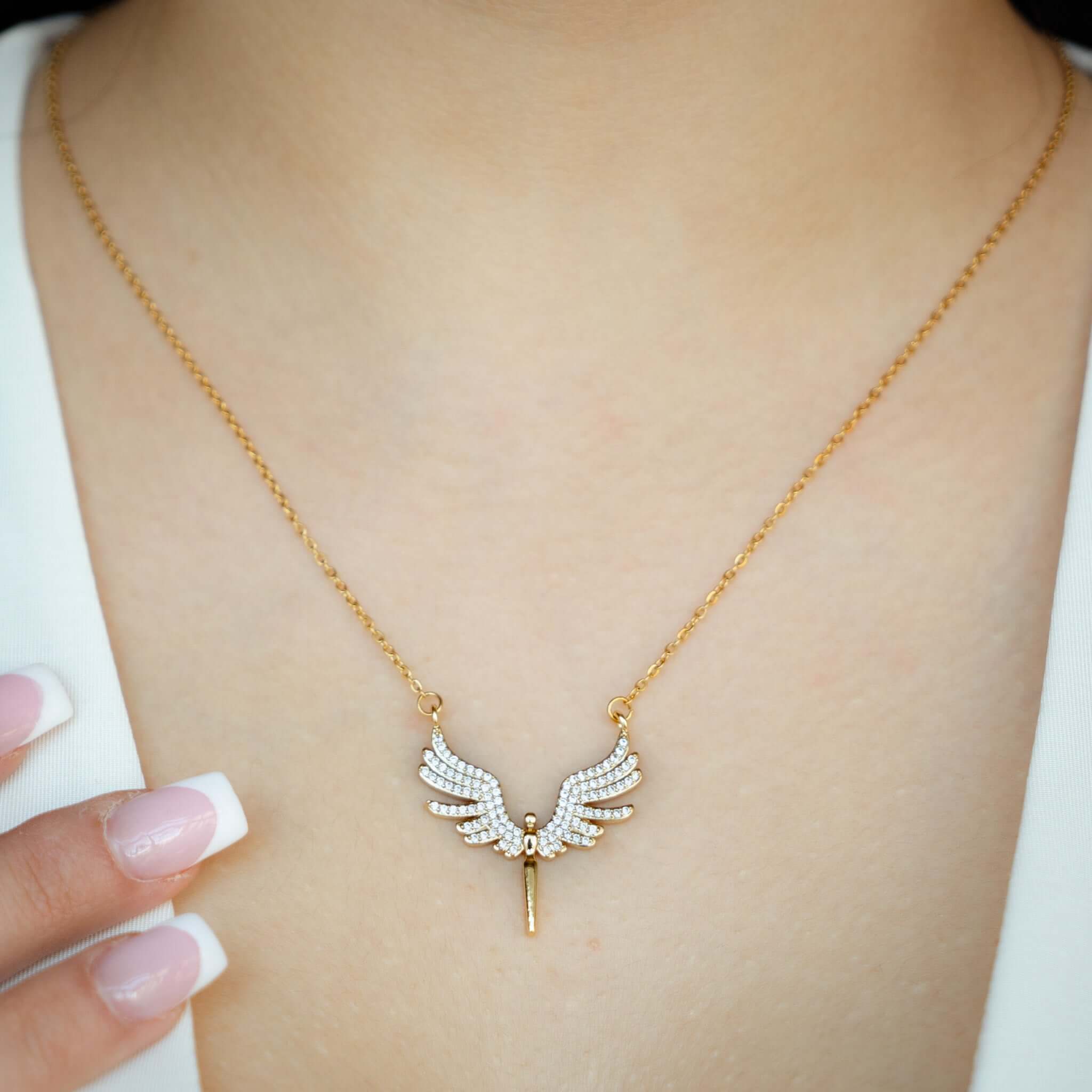 Gold Engelsflügel Halskette mit funkelnden Kristallen, elegant getragen auf dem Hals einer Person.
