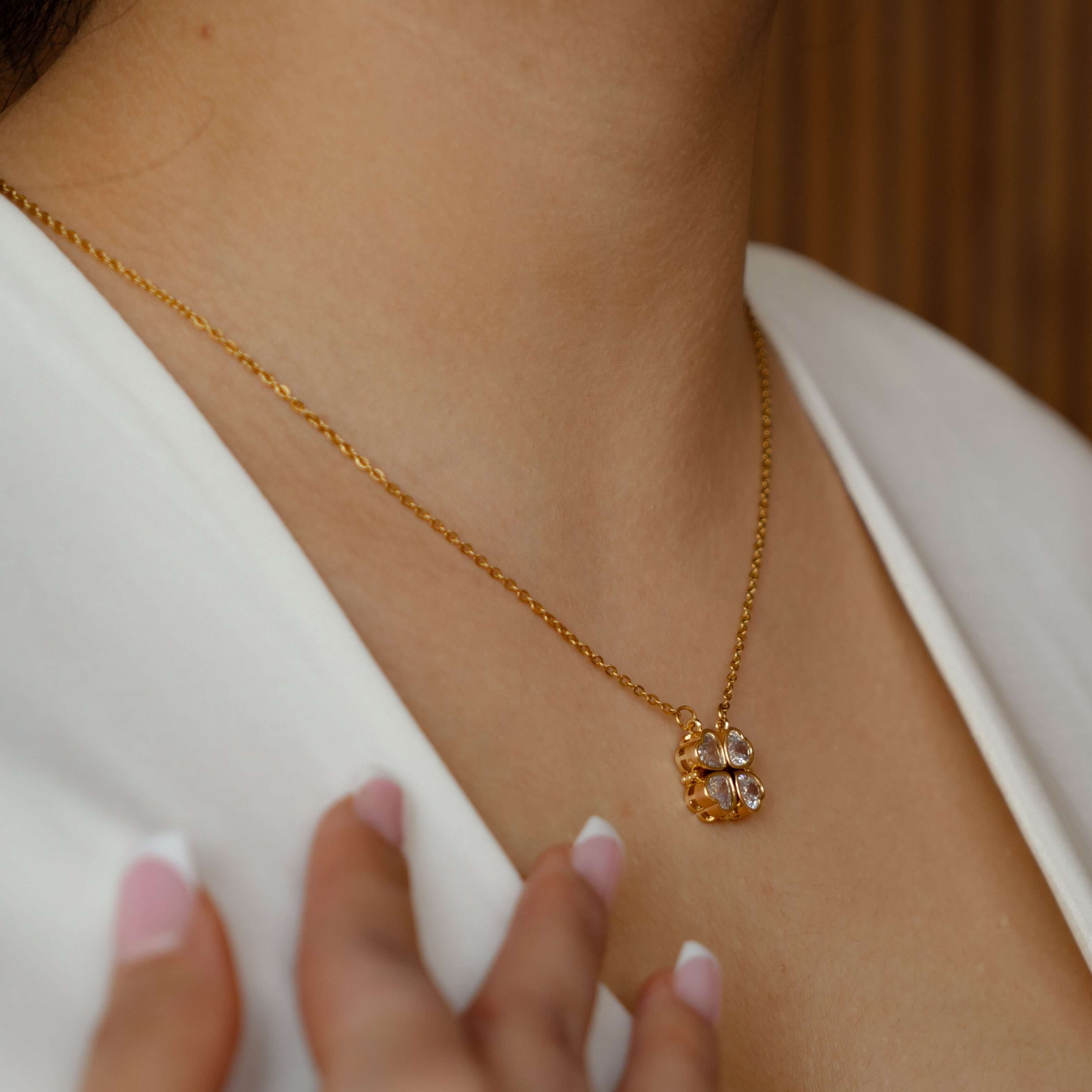 Goldene Herz-Kleeblatt Halskette aus Edelstahl mit funkelnden Strasssteinen, getragen von einer Person.