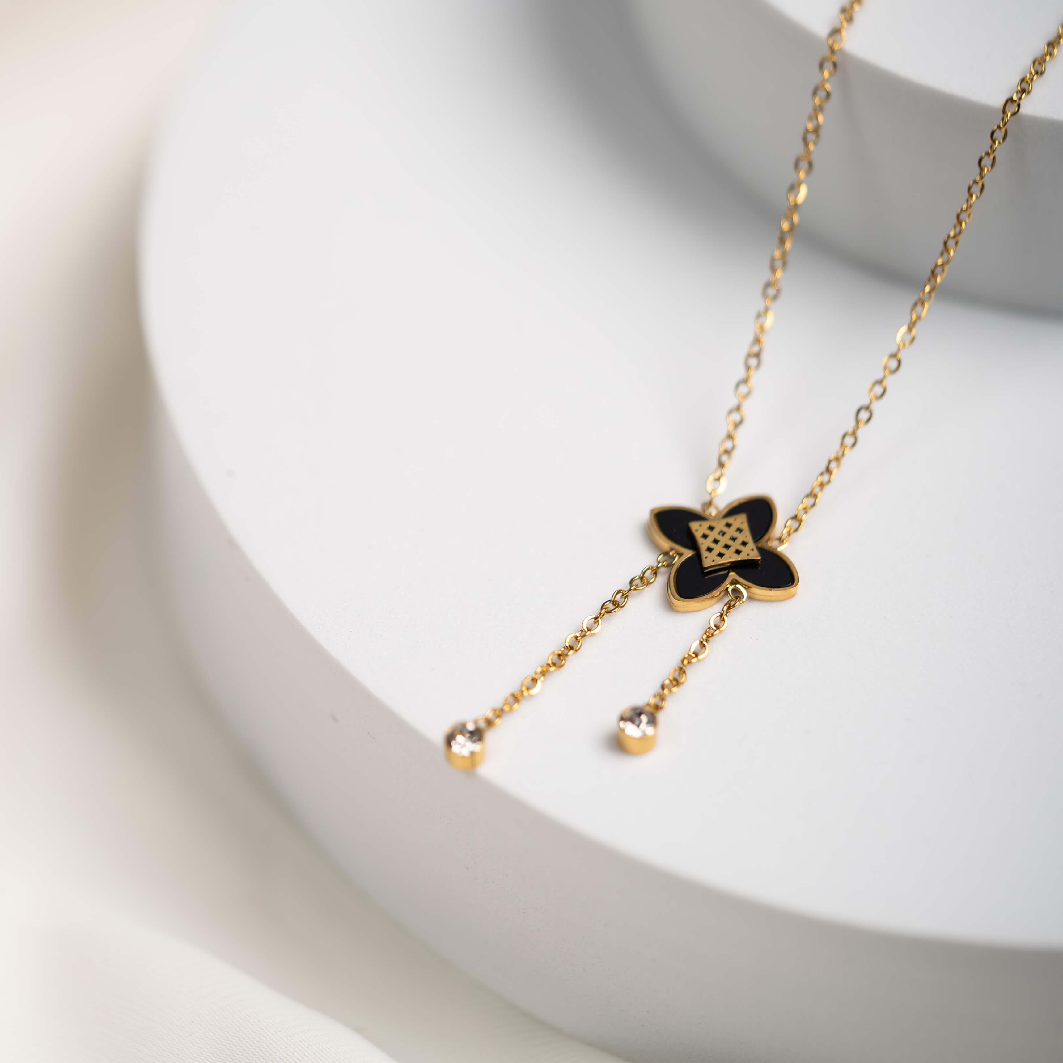 Goldene Kleeblattkette mit Kristallanhängern auf hellem Hintergrund, elegantes Schmuckdesign.